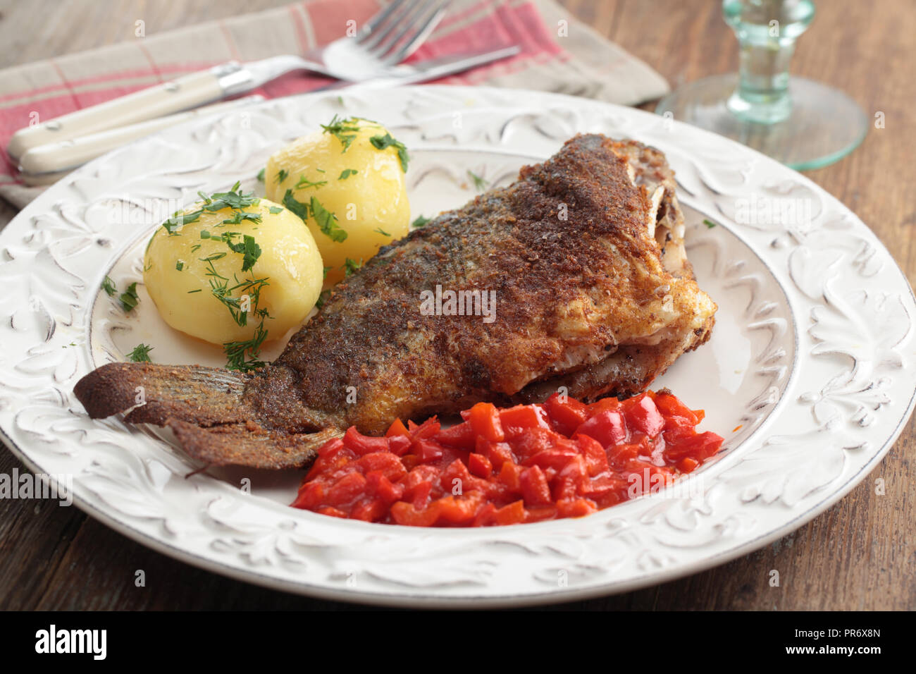Roasted whole  carp with potatoes on a rustic table Stock Photo