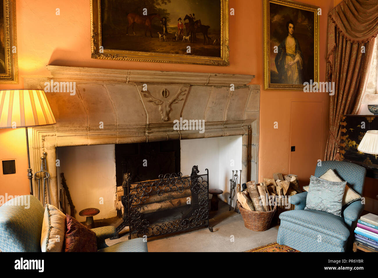 Drawing Room at Cawdor Castle Scotland with plush chairs around fireplace staghead buckle emblem and framed family paintings Stock Photo