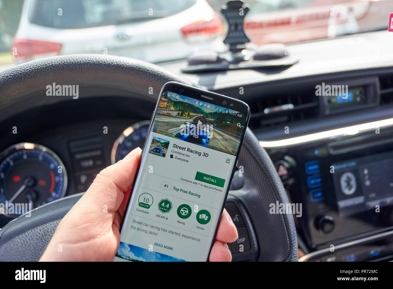 MONTREAL, CANADA - AUGUST 8, 2018: Street Racing 3d android mobile video game on Samsung s8 screen in a mans hand in a car. Stock Photo