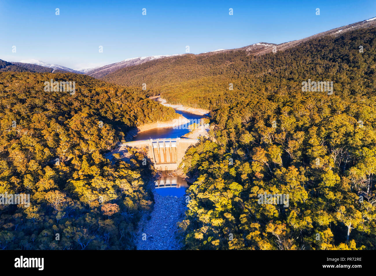 Massive concrete Guthega dam on Snowy river blocking flow and forming fresh water reservoir and generating renewable energy in Snowy mountains between Stock Photo