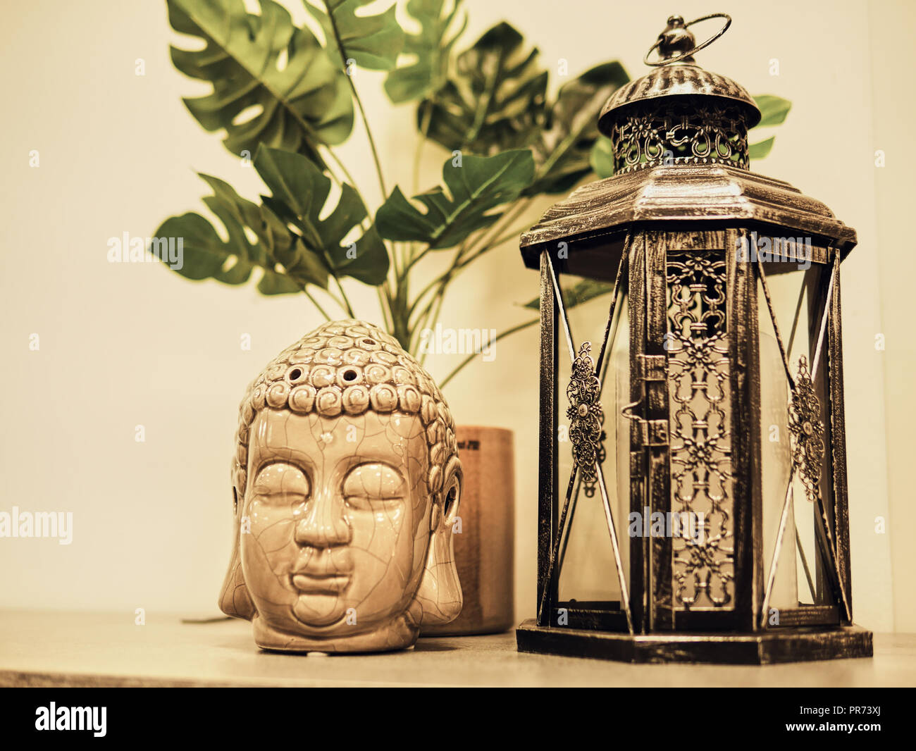 Buddah statue in modern home, Home decoration. Candle Lighter and Buddha Head statue and Monstera's Leaves. Holidays decoration Stock Photo