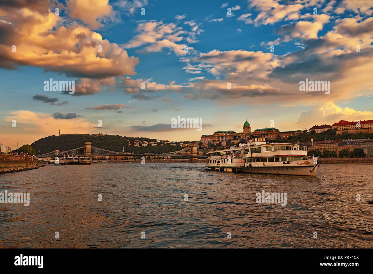 Beautiful Szechenyi Chain Bridge with sightseeing boat on River Danube and Buda Castle Royal Palace on sunset Stock Photo