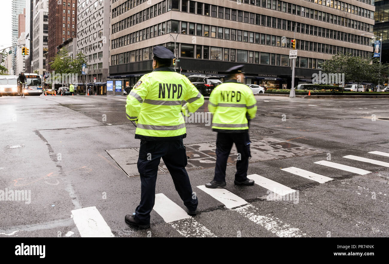 New York City police officers direct traffic at the intersection of Park Avenue and East 57th Street on a rainy morning. Stock Photo