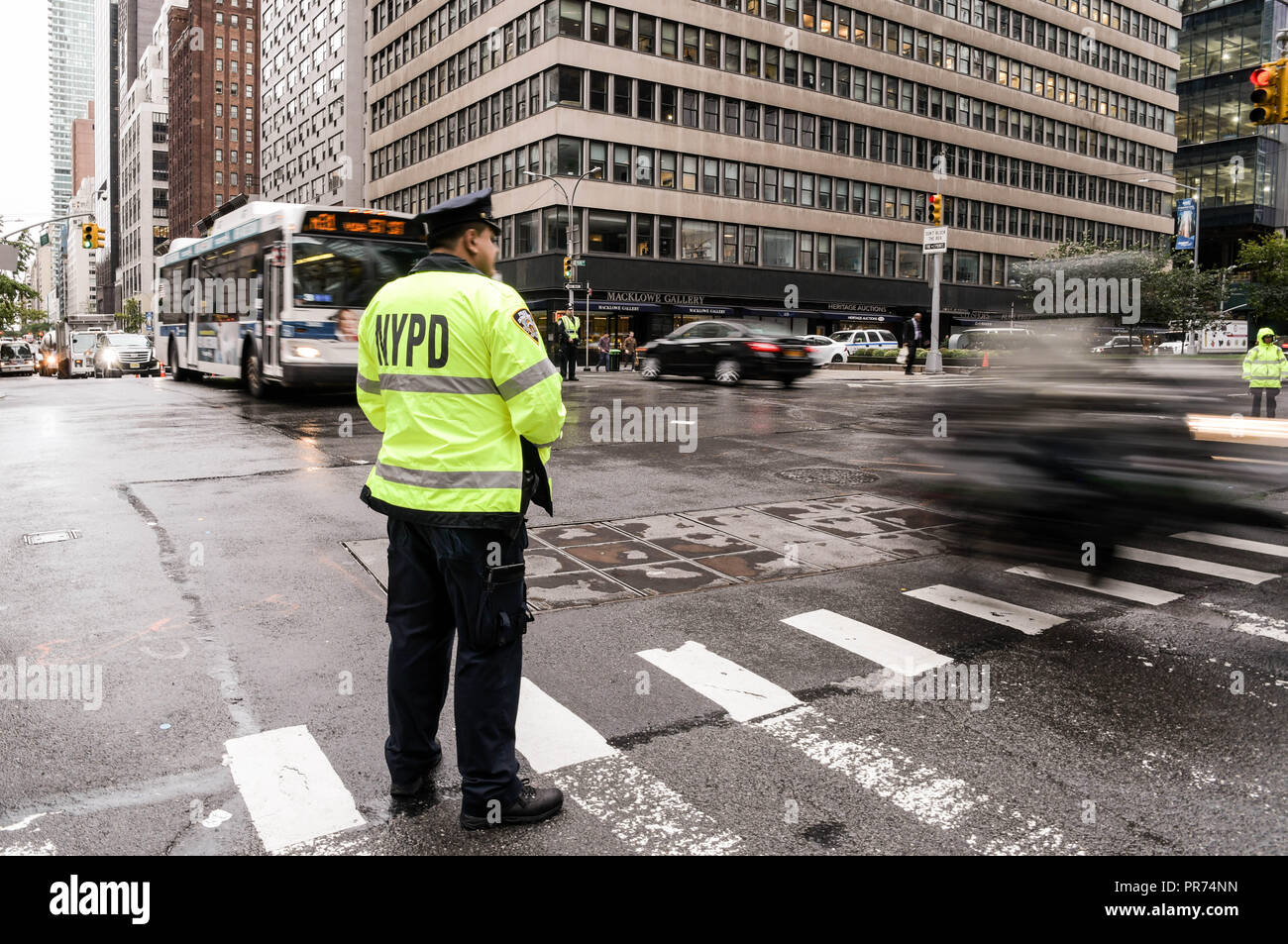 New York City police officers direct traffic at the intersection of Park Avenue and East 57th Street on a rainy morning. Stock Photo