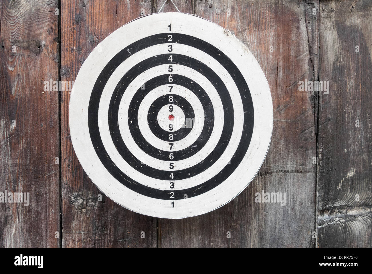 round circular black and white target with numbers hanging on a wooden wall up close and in detail Stock Photo