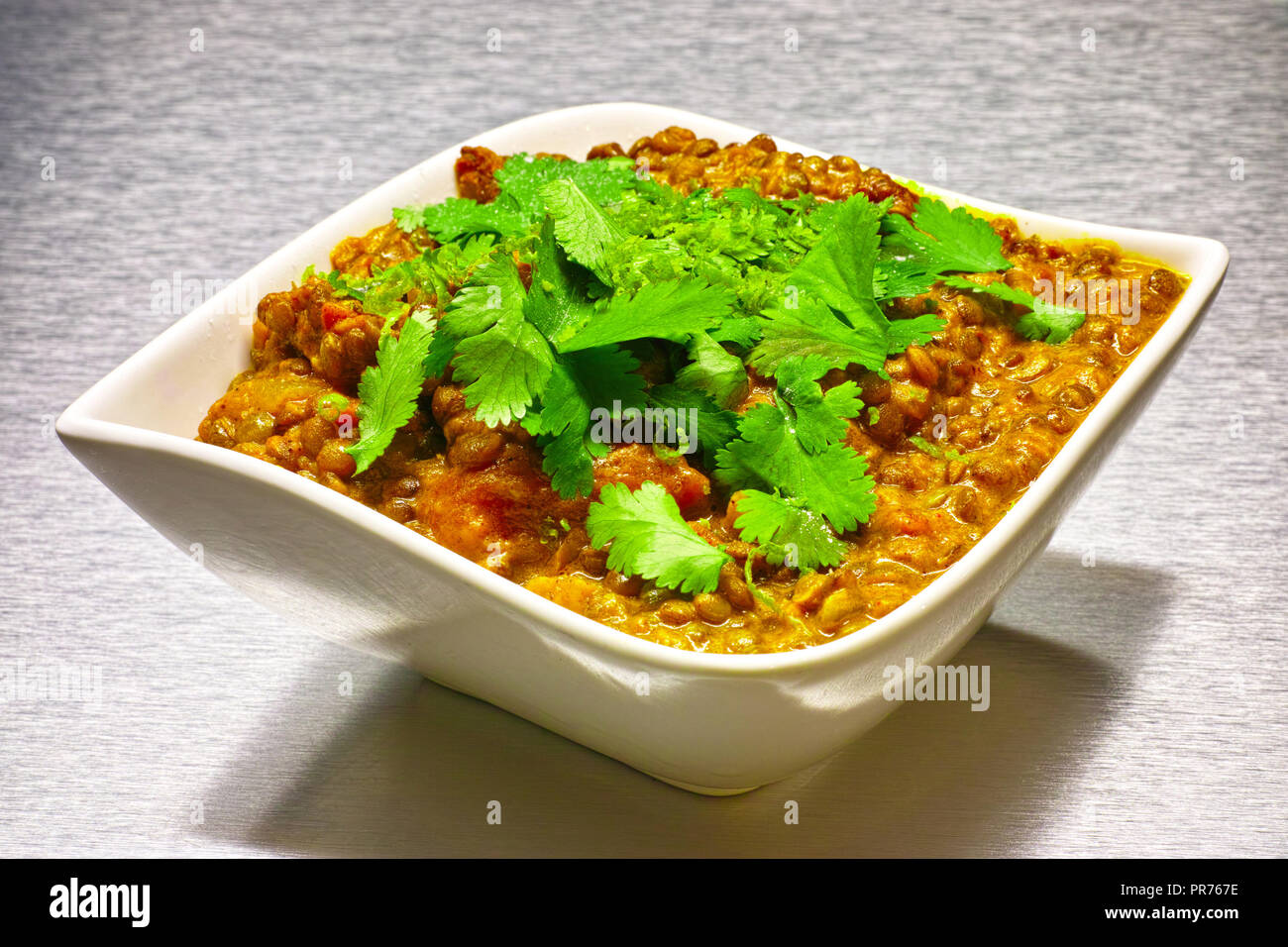 Moong Dahl, indian vegetarian lentil soup, in white bowl. Aluminium background. Stock Photo