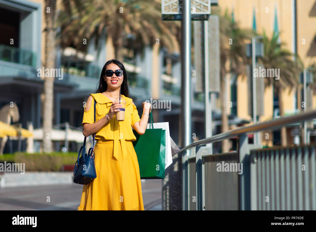 Asian girl with shopping bags and coffee to go outdoors Stock Photo