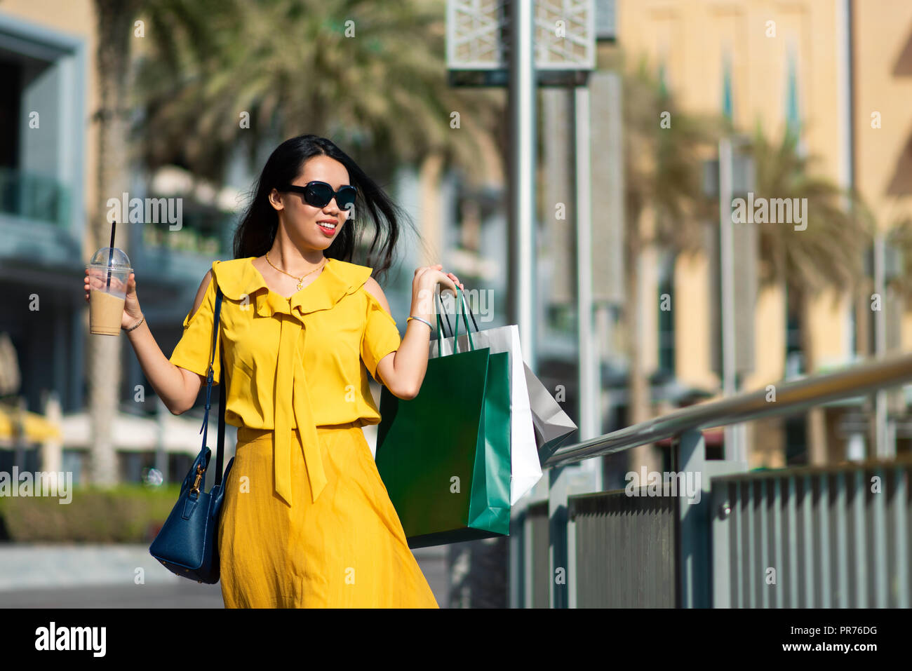Asian girl with shopping bags and coffee to go outdoors Stock Photo