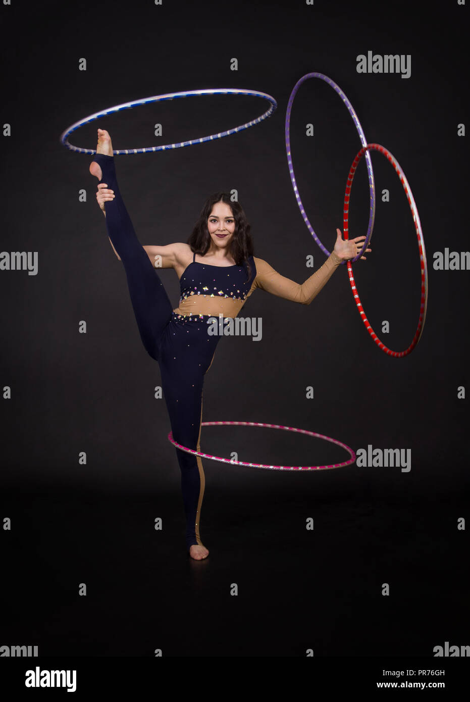 Gymnastic exercises with hula-Hoop woman performs circus performer in an  artistic costume. Studio shooting on a dark background Stock Photo - Alamy