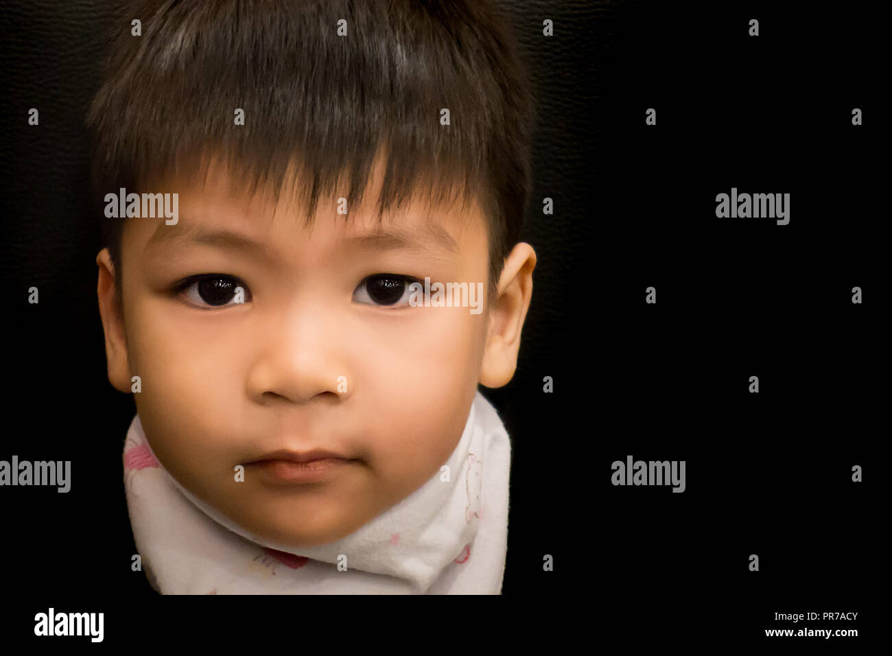 Sad Asian boy portrait on black background. Stock Photo