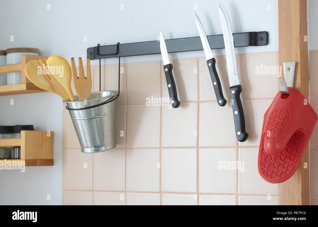 Wooden spatulas in a holder and kitchen knives on a rack Stock