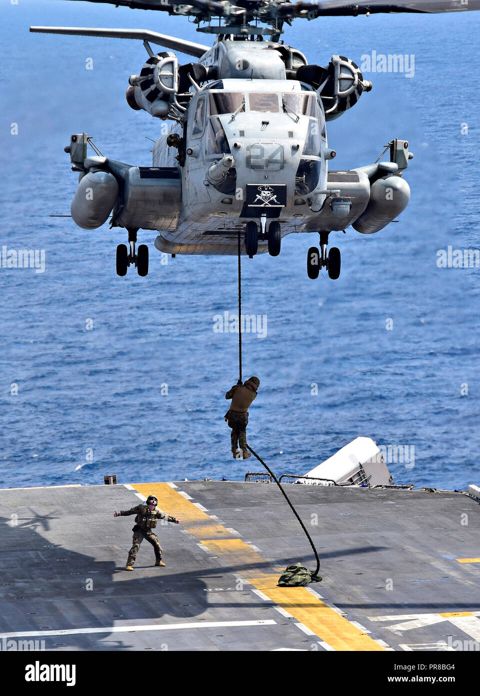 SOUTH CHINA SEA (Sept. 25, 2018) - Marines assigned to the 31st Marine Expeditionary Unit (MEU) rappel down a rope from a CH-53E Super Stallion helicopter assigned to the 'Flying Tigers' of Marine Medium Tiltrotor Squadron (VMM) 262 reenforced, as it hovers over the flight deck of the amphibious assault ship USS Wasp (LHD 1) during a fast rope exercise. Wasp, flagship of the Wasp Amphibious Ready Group, with embarked 31st MEU, is operating in the Indo-Pacific region to enhance interoperability with partners and serve as a ready-response force for any type of contingency. (U.S. Navy photo by Ma Stock Photo