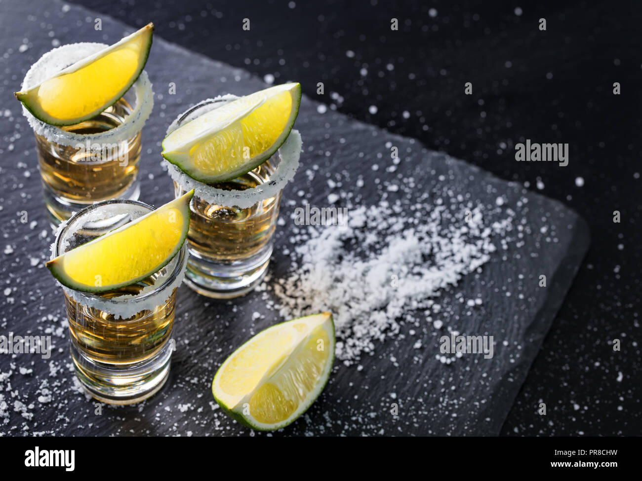 Tequila glasses with salt on the rim and lime on a black backgroundю ...