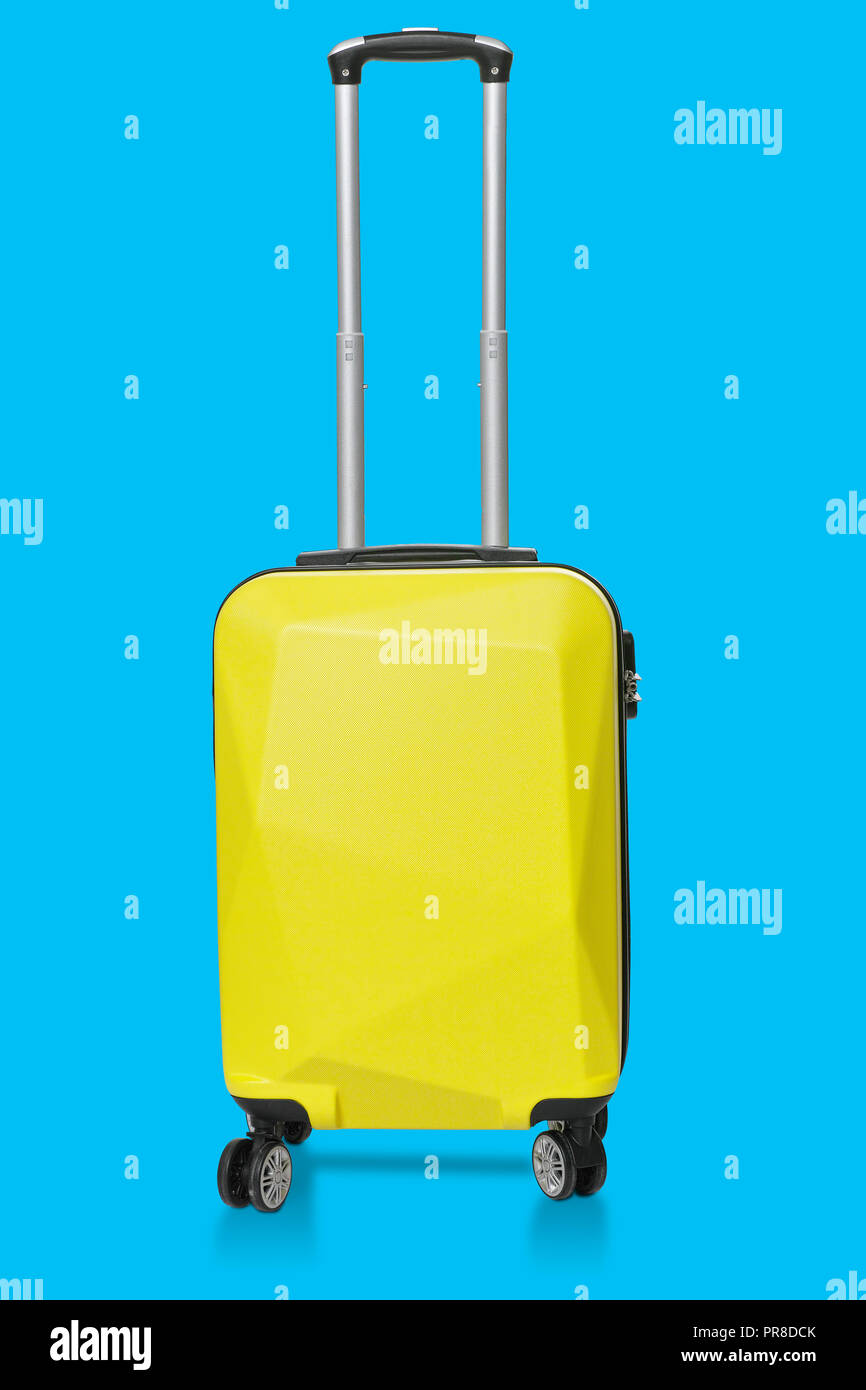 Yellow plastic luggage isolated on blue background with clipping path on suitcases object Stock Photo