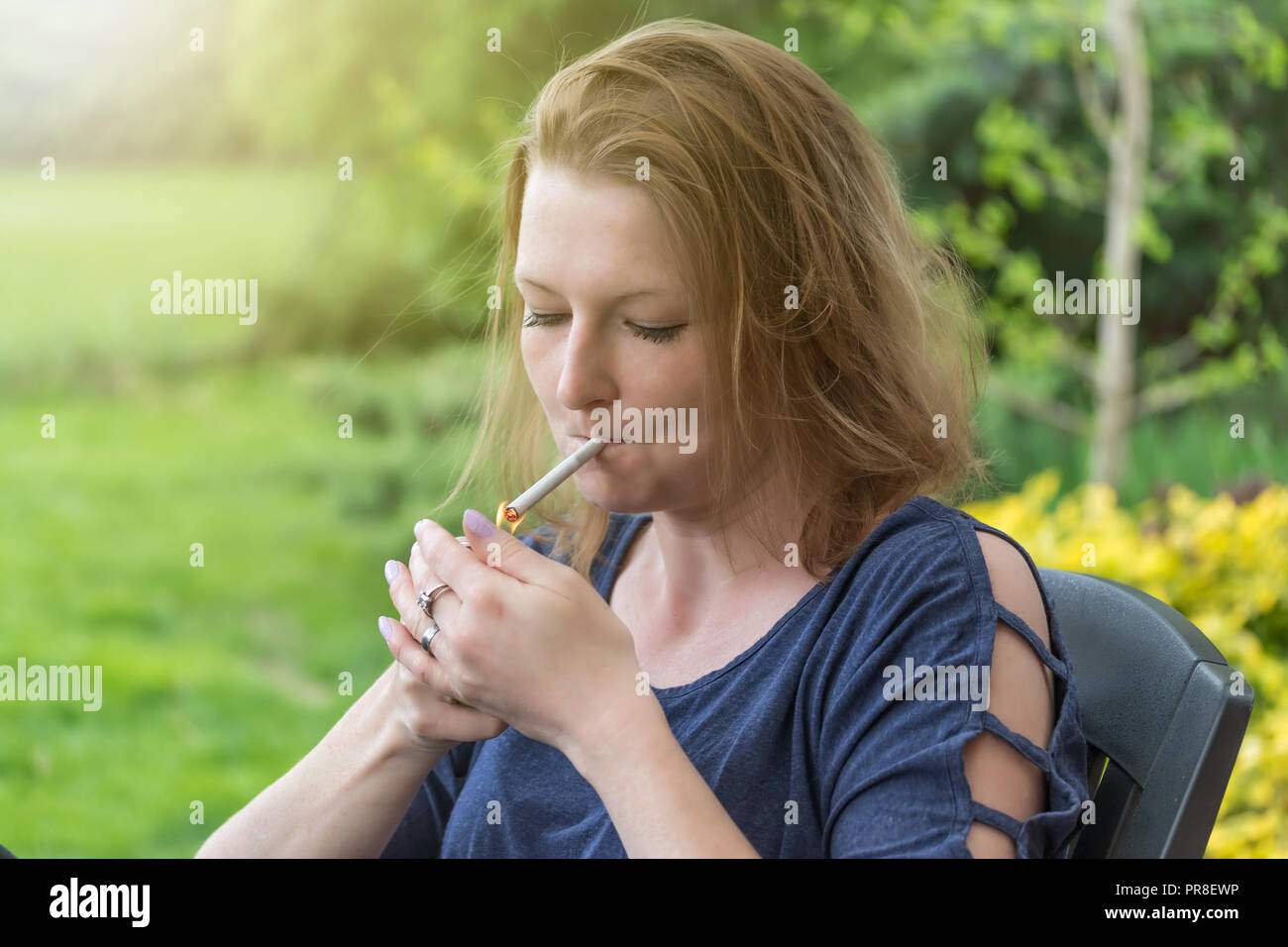 Beautiful young woman lighting cigarette hires stock photography and