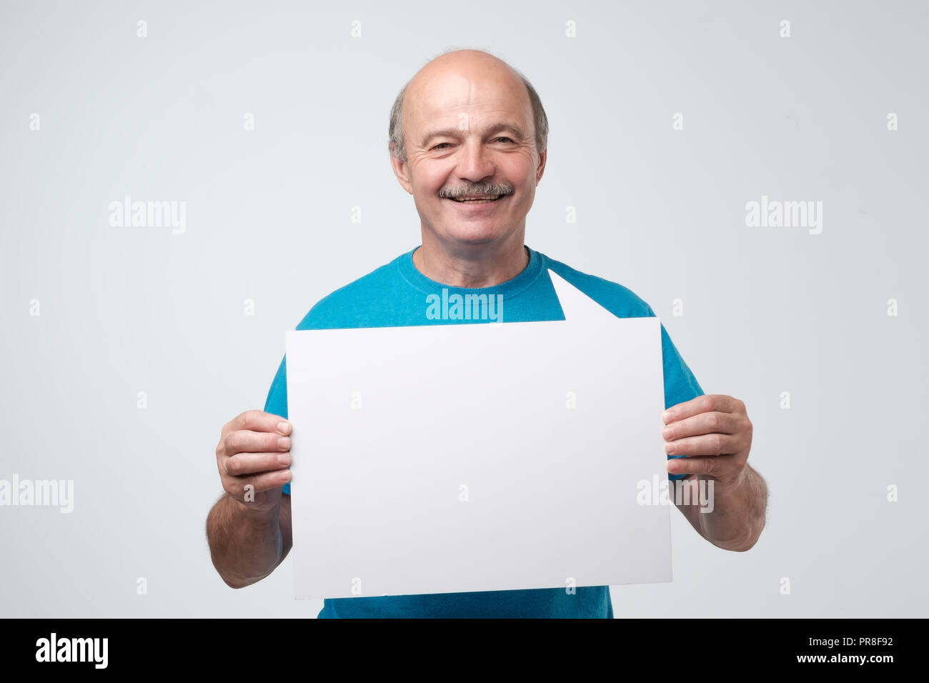 Senior hispanic man with mustache holds the white sign in a studio