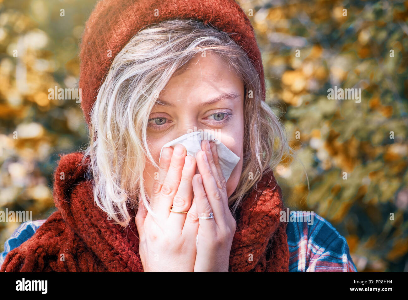 Girl feeling sick blowing nose outdoor in the park Stock Photo
