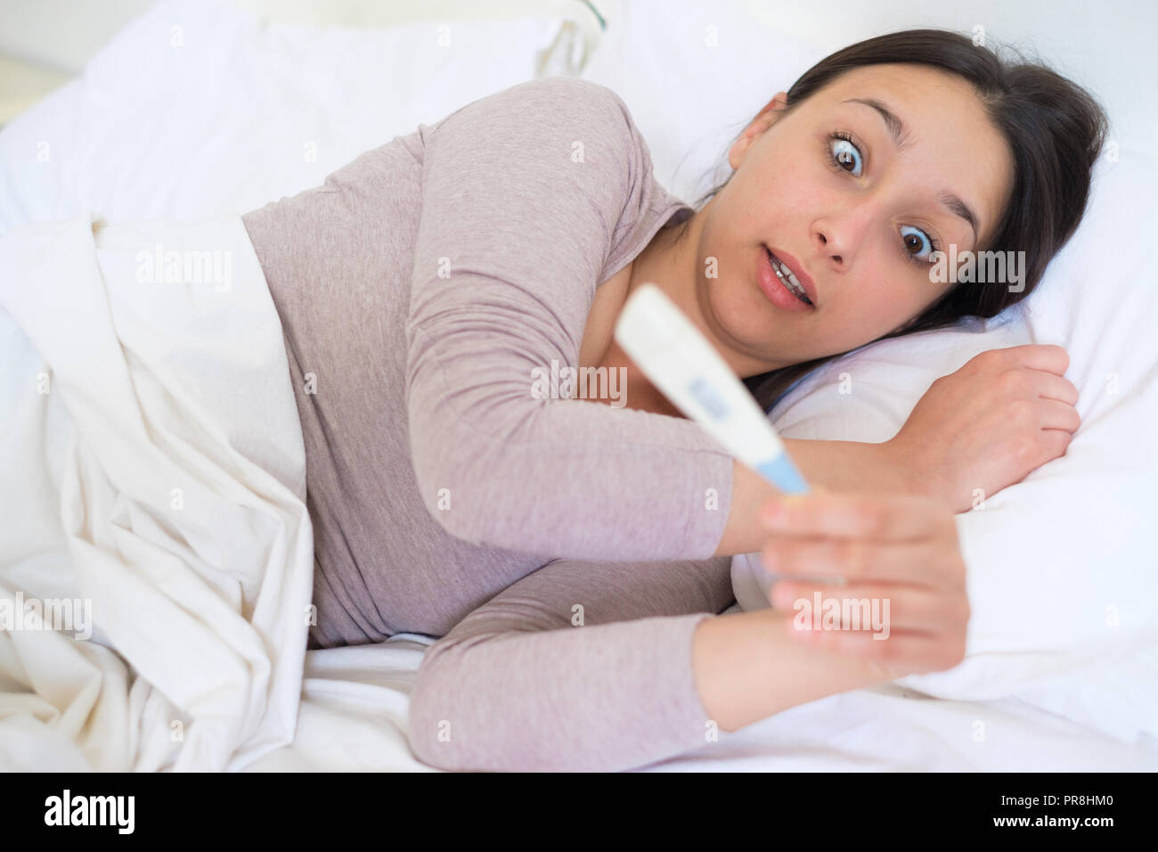 Surprised woman reading positive test result Stock Photo