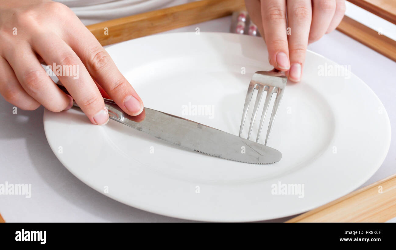 Concept of diet and loosing weight. Female hands holding fork and knife
