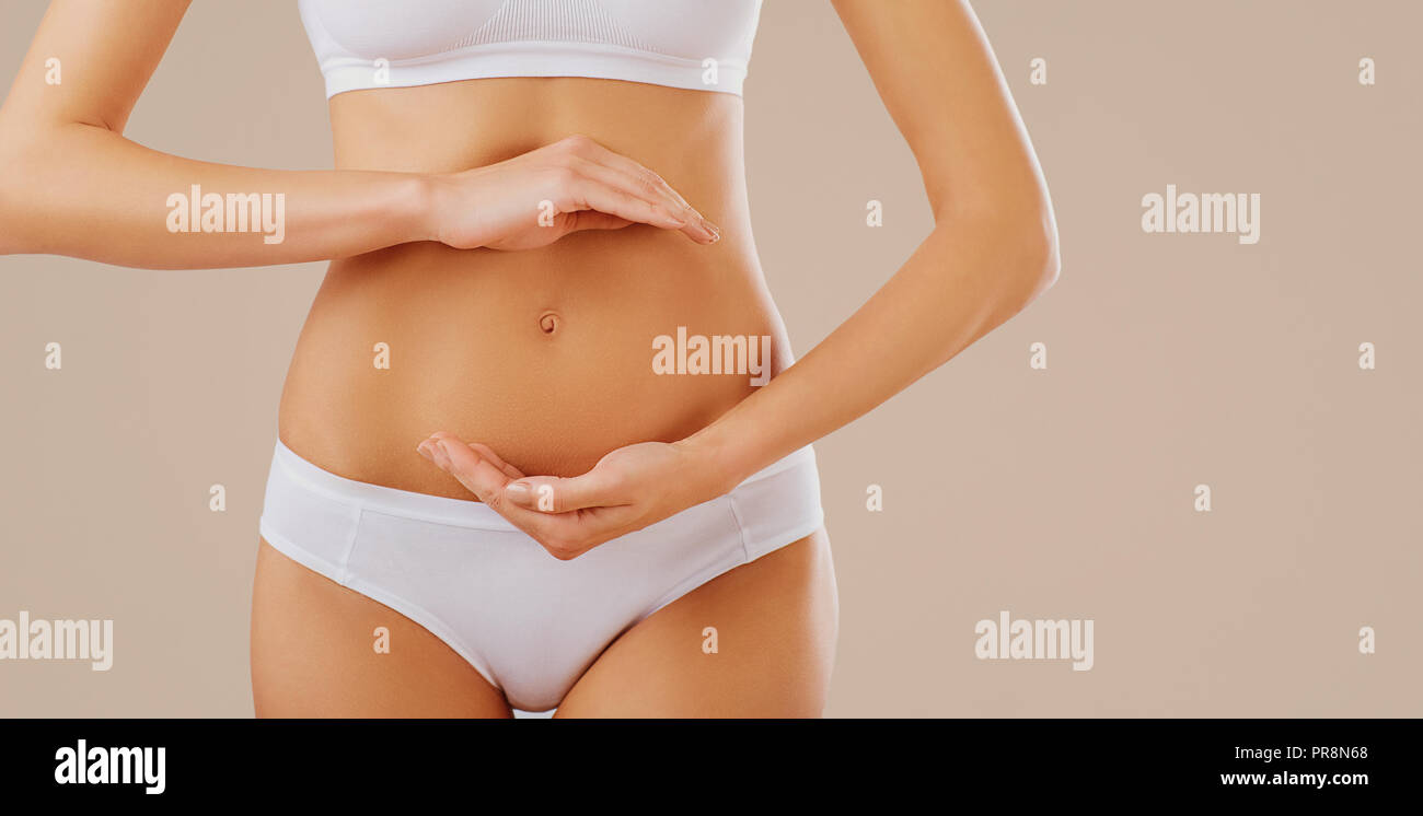 A woman holds her hands at the belly. Stock Photo