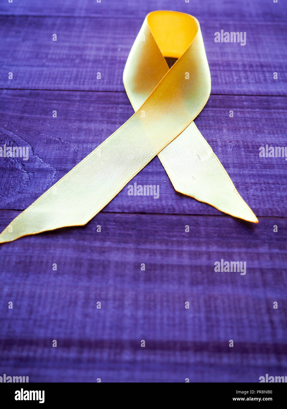 Childhood Cancer Day. Yellow Ribbon on blue background. Stock Photo