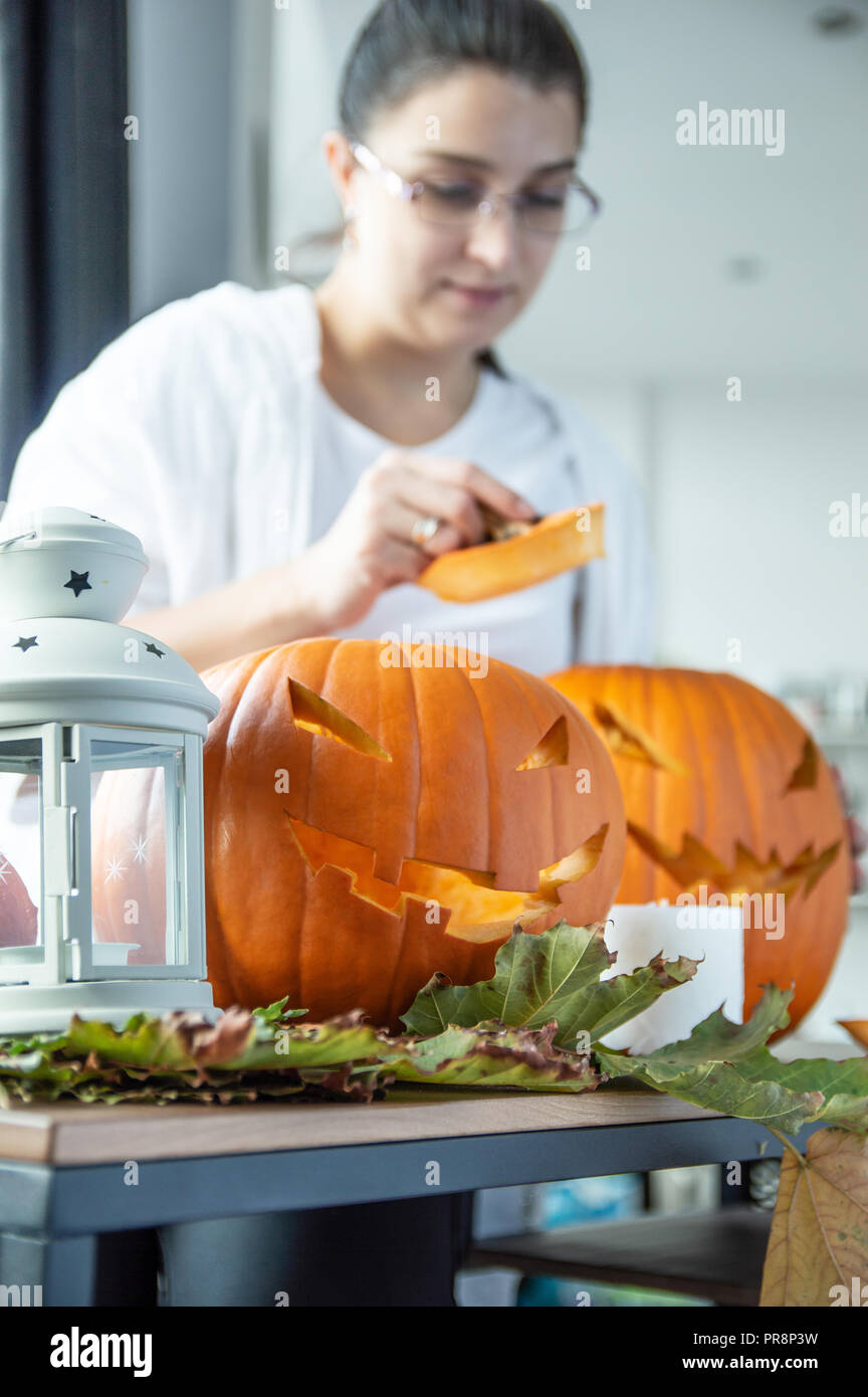 Pumpkins prepared for Halloween lie on the table with woman in background Stock Photo