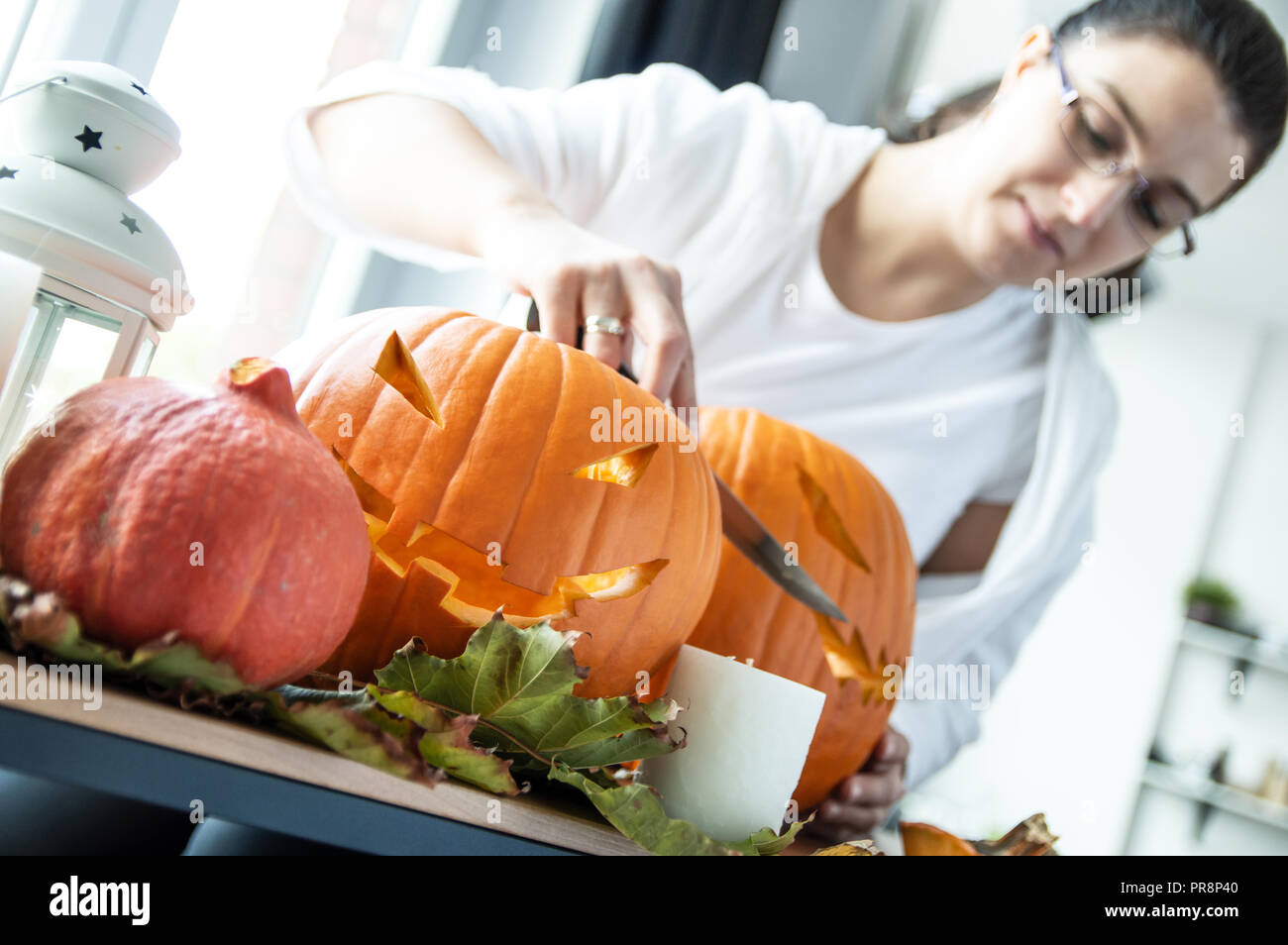 Young woman prepares pumpkins as decoration for Halloween Stock Photo