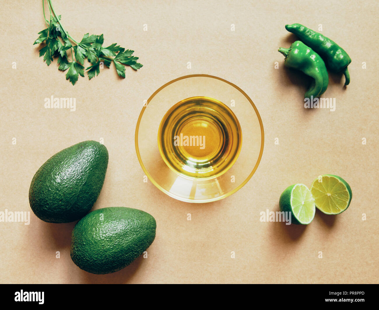 Avocado oil lemon and green pepper over a brown above view Stock Photo