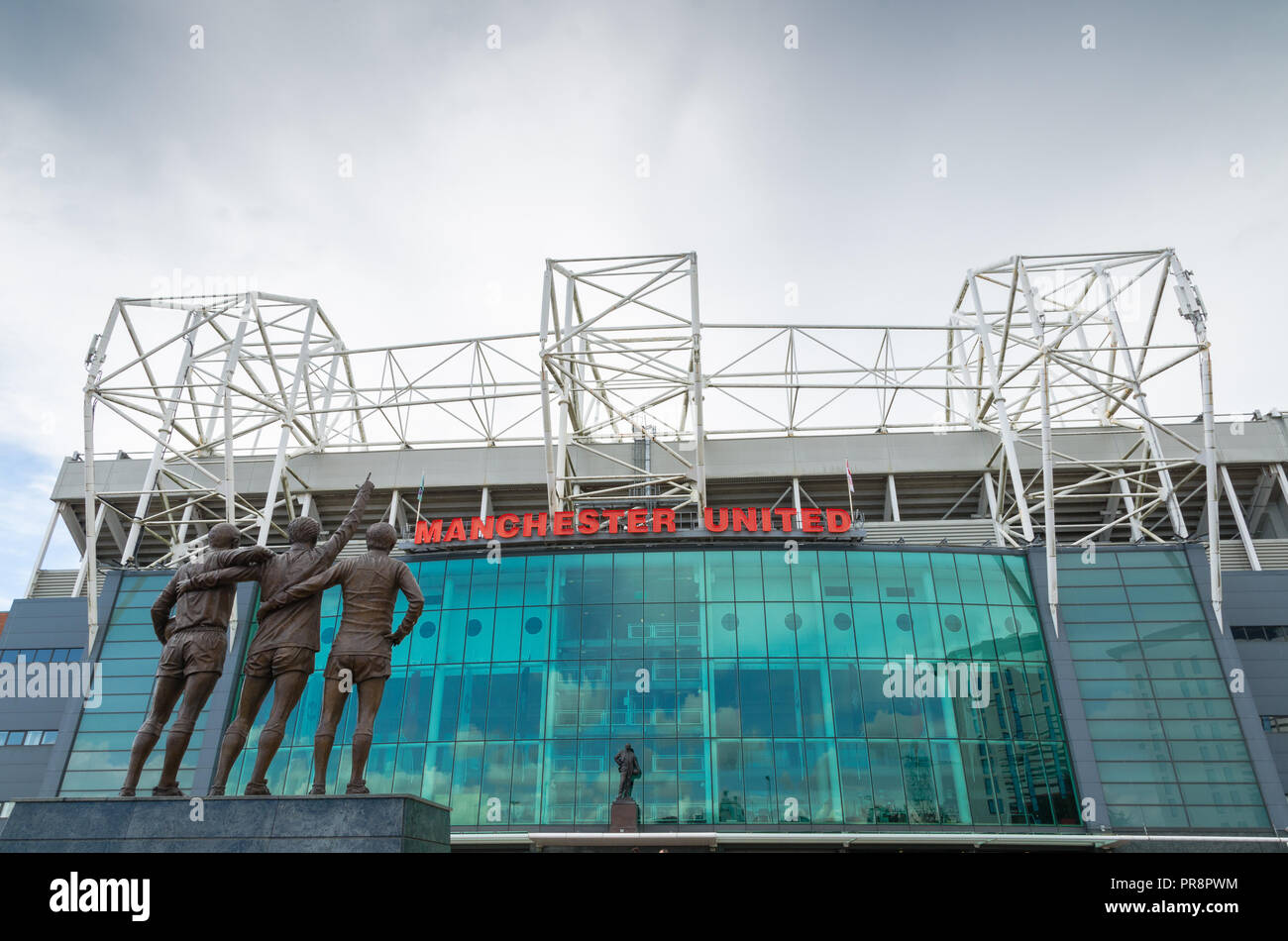 The 'Holy Trinity' statue commemorating Dennis Law, Sir Bobby Charlton and George Best at the front façade at Old Trafford, Manchester Stock Photo