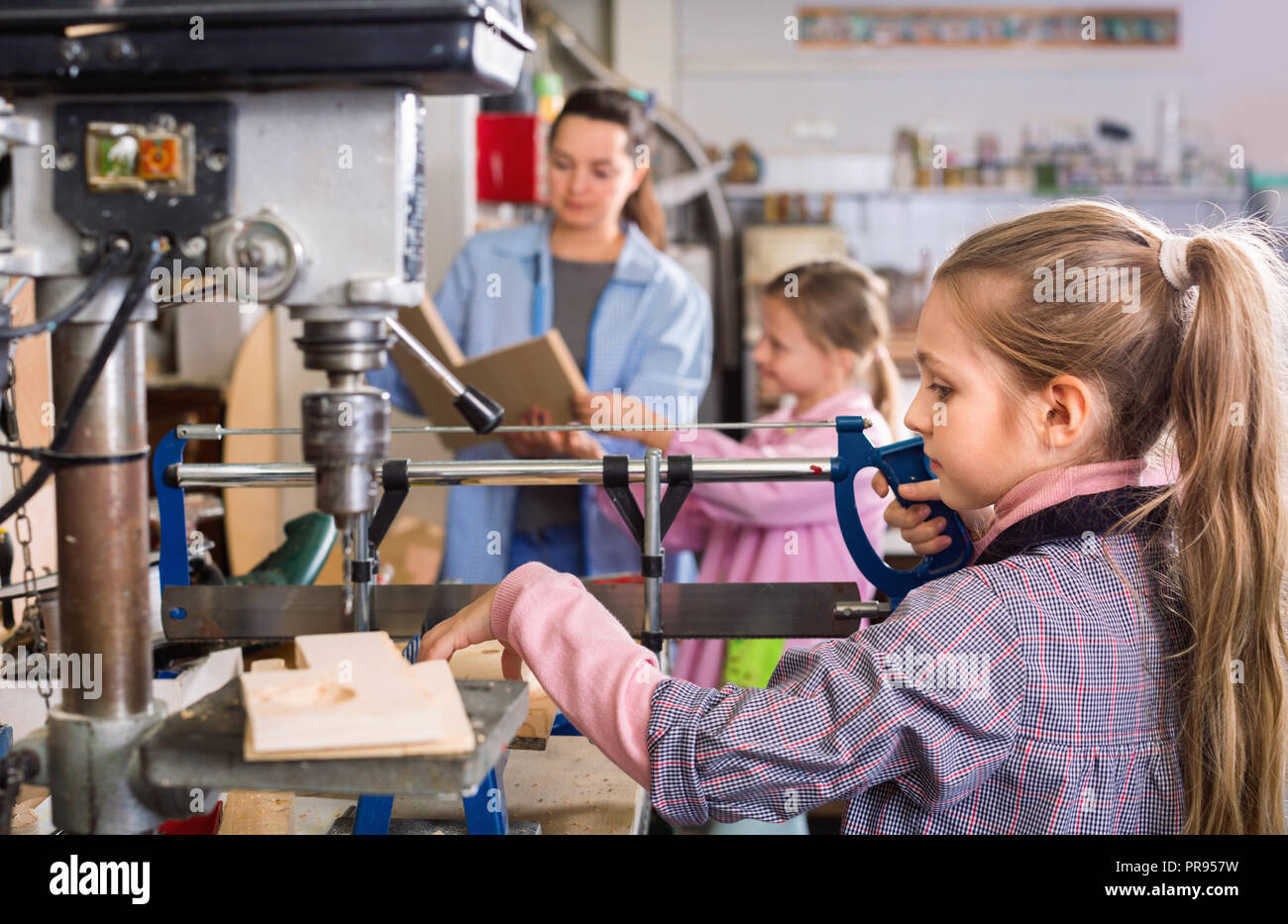Smiling happy cheerful schoolgirls learning to carve wood during arts