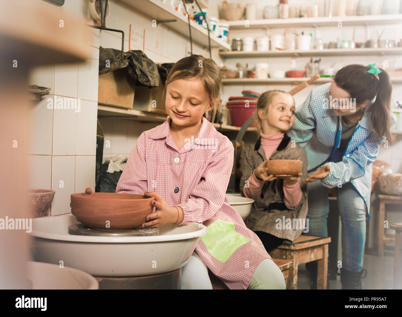 Cheerful positive schoolgirls learning from teacher to make ceramics during arts and crafts class Stock Photo