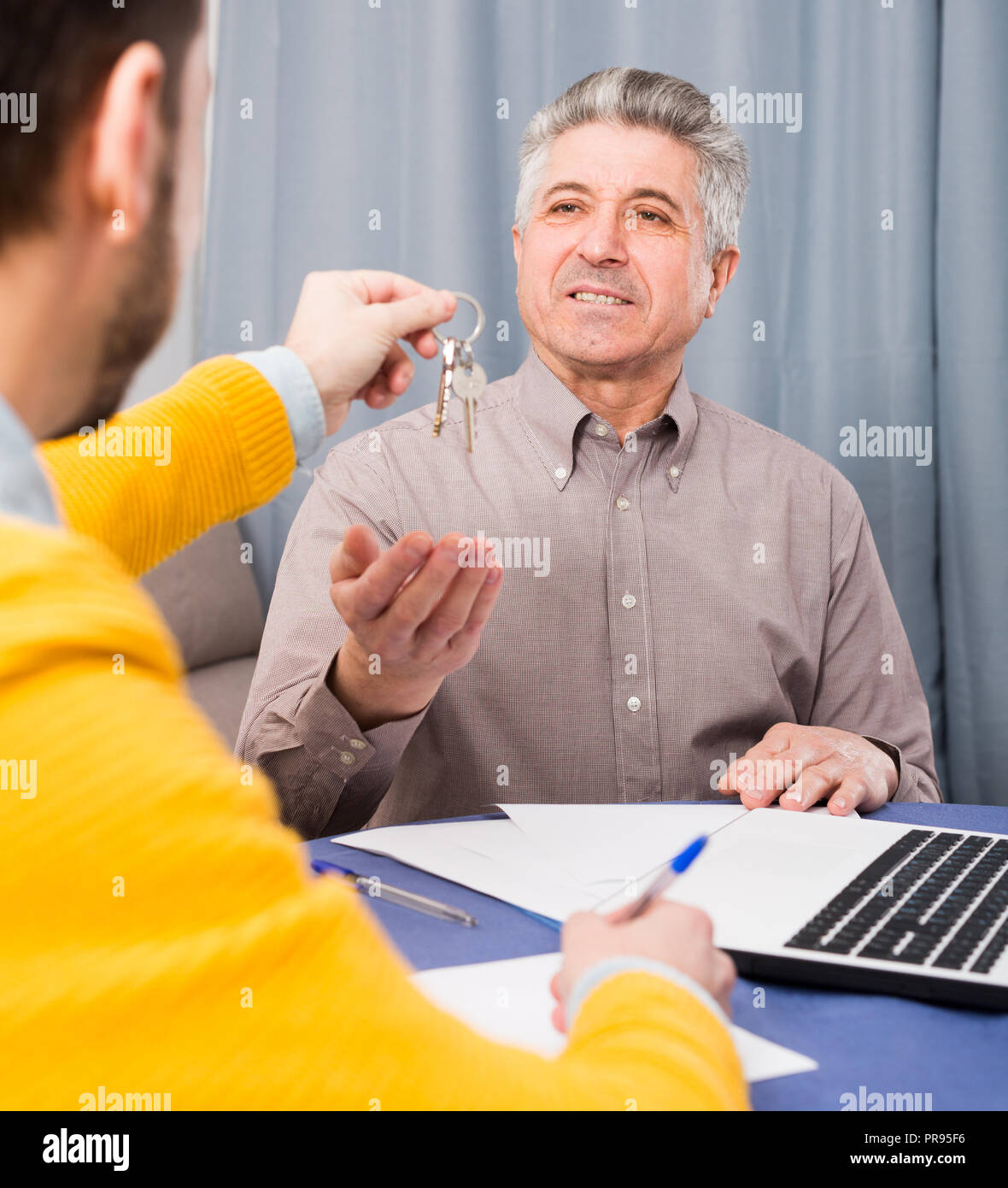 Mature man and young agent sign contract of rent apartments and hand