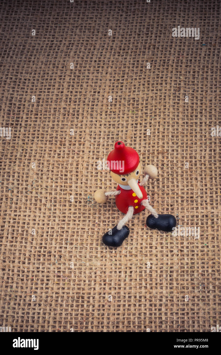 Wooden Pinocchio doll sitting on canvas background Stock Photo - Alamy