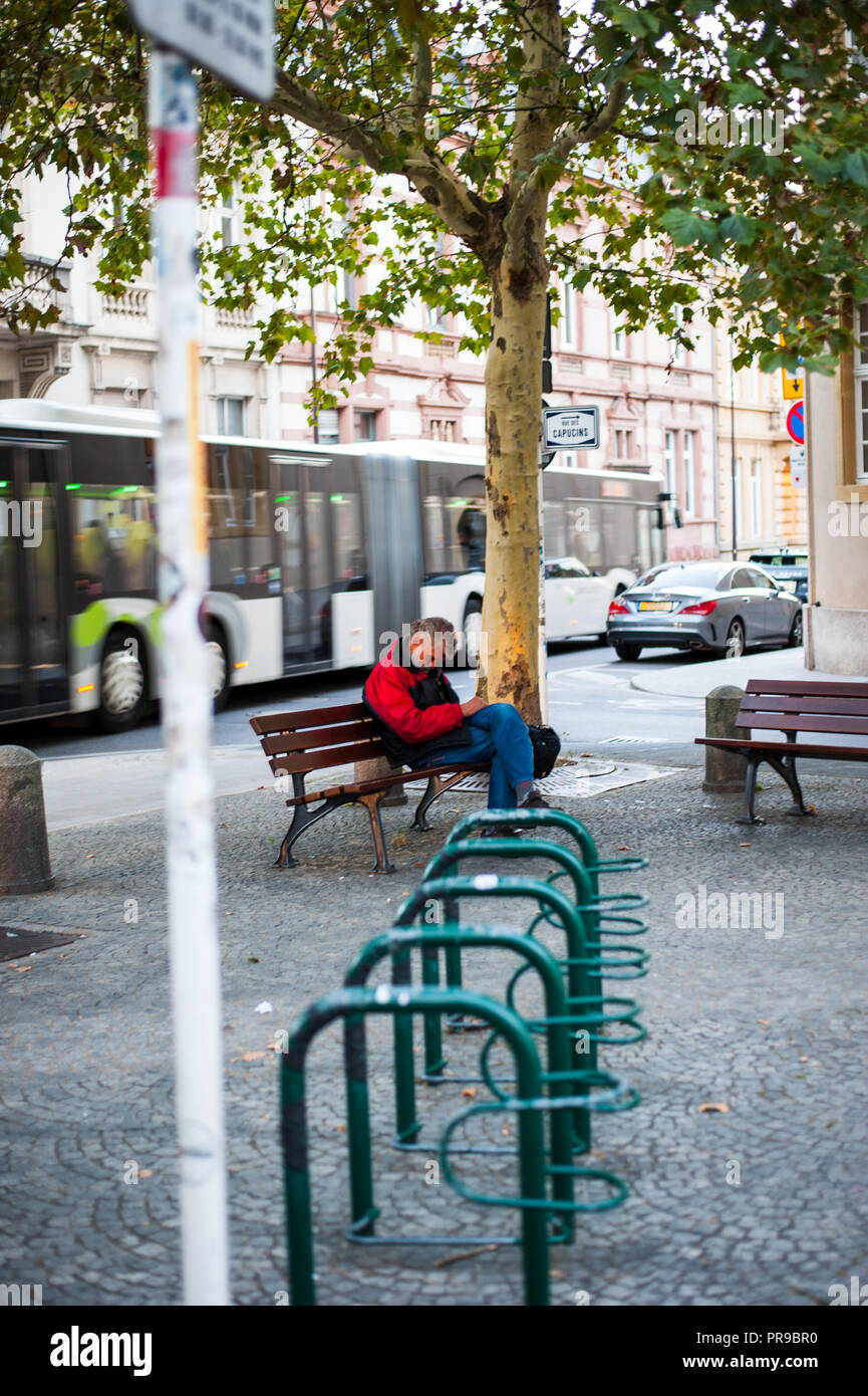A man sleeping on a bench in the street Stock Photo - Alamy