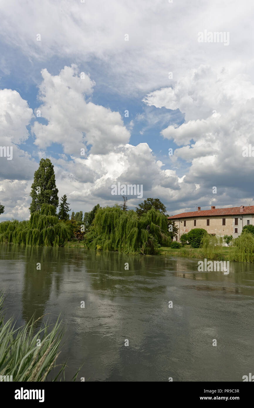 Farmhouse by the river with cloudy sky Stock Photo - Alamy