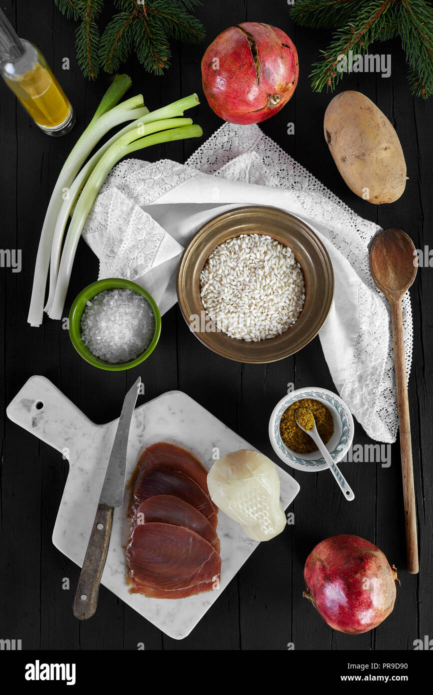 Ingredients for the risotto recipe with scamorza cheese and smoked tuna fish. Photographed from above, on a black wooden background. Stock Photo
