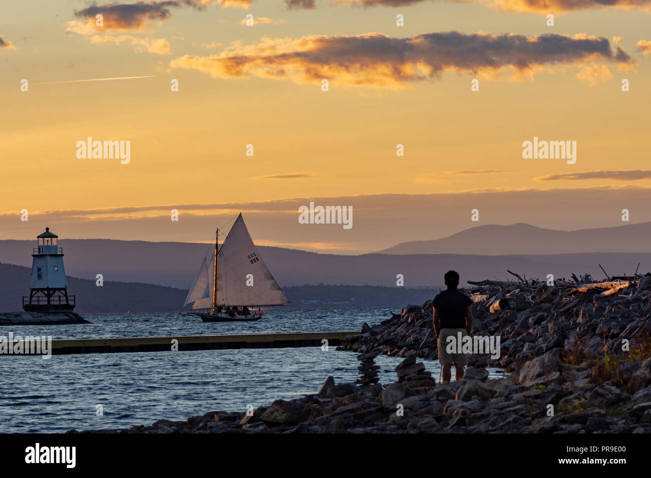 Tourist watching a sailboat pass by on Lake Champlain Stock Photo