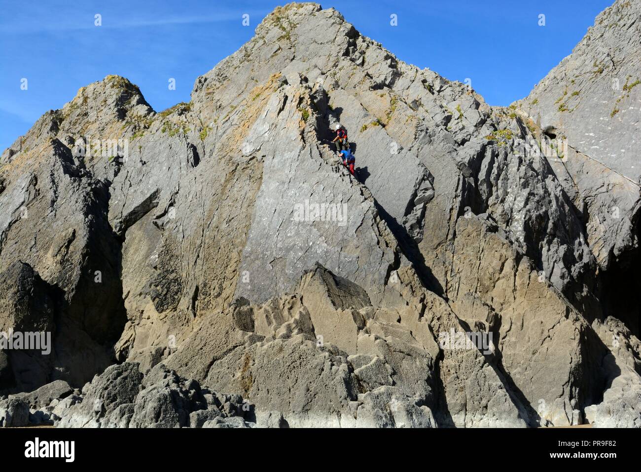 Two men rock climbing climbers on Three Cliffs Three Cliffs Bay Gower Peninsula Wales Cymru UK