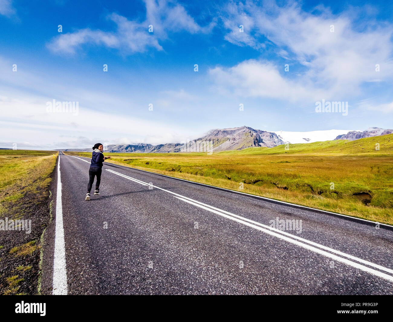 female traveler running into the horizon on the Ring Road in Iceland Stock Photo