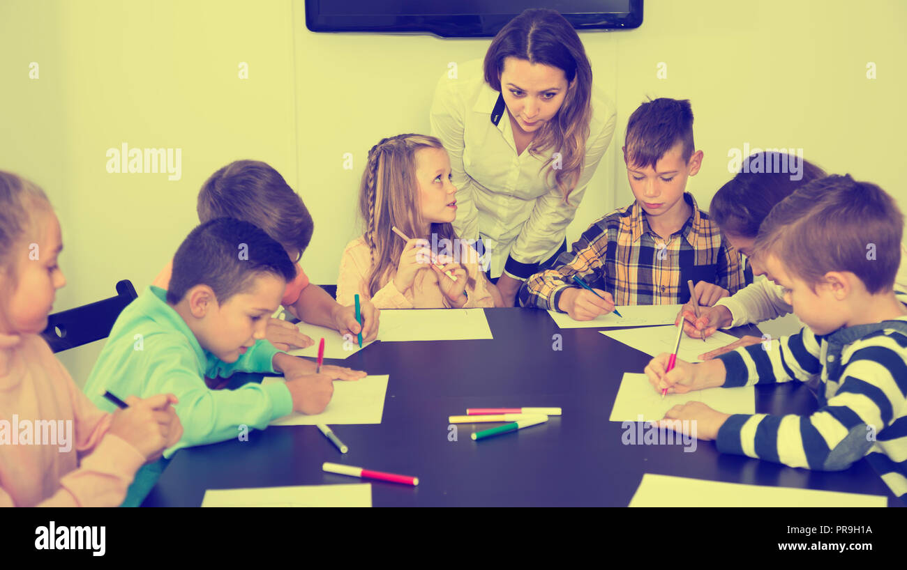 Little children with speaking teacher drawing in classroom on the ...