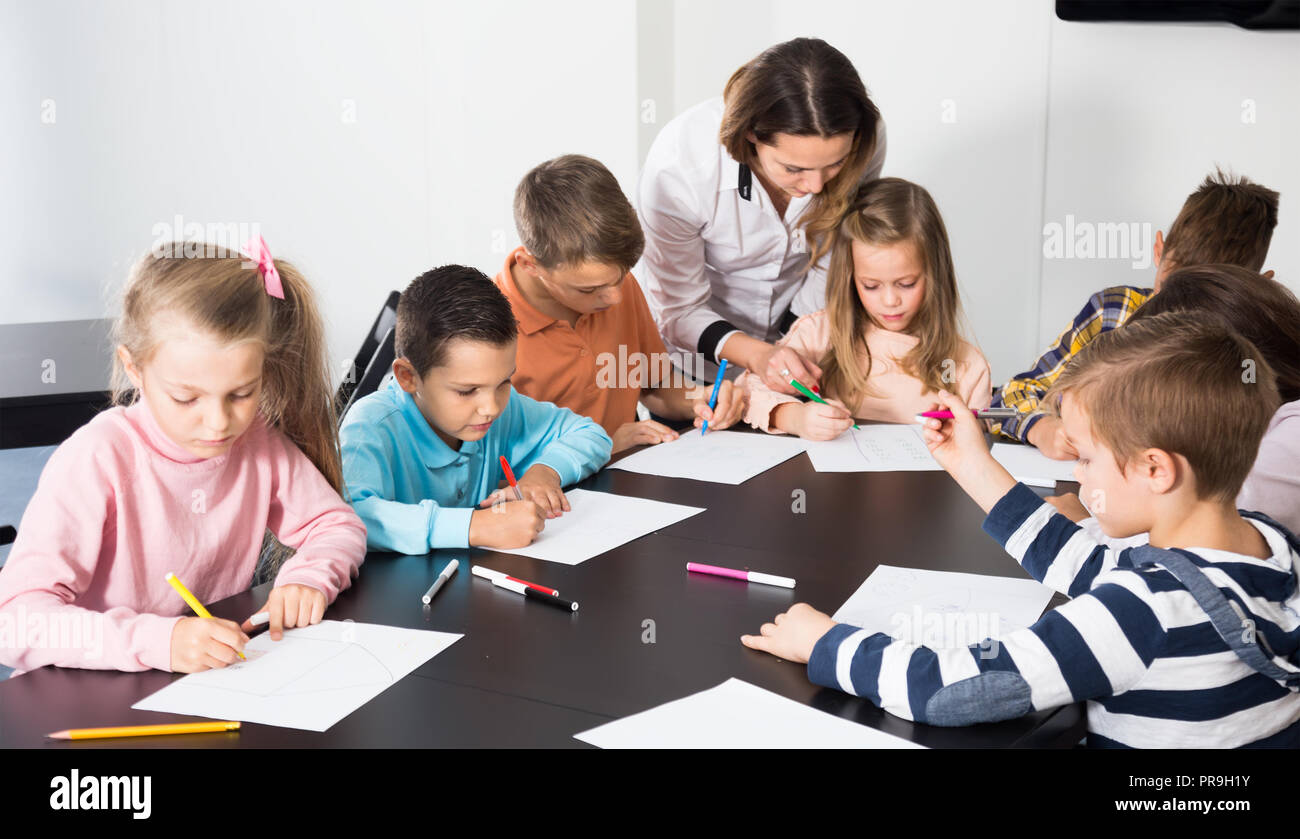 satisfied little children with teacher drawing in classroom on the ...