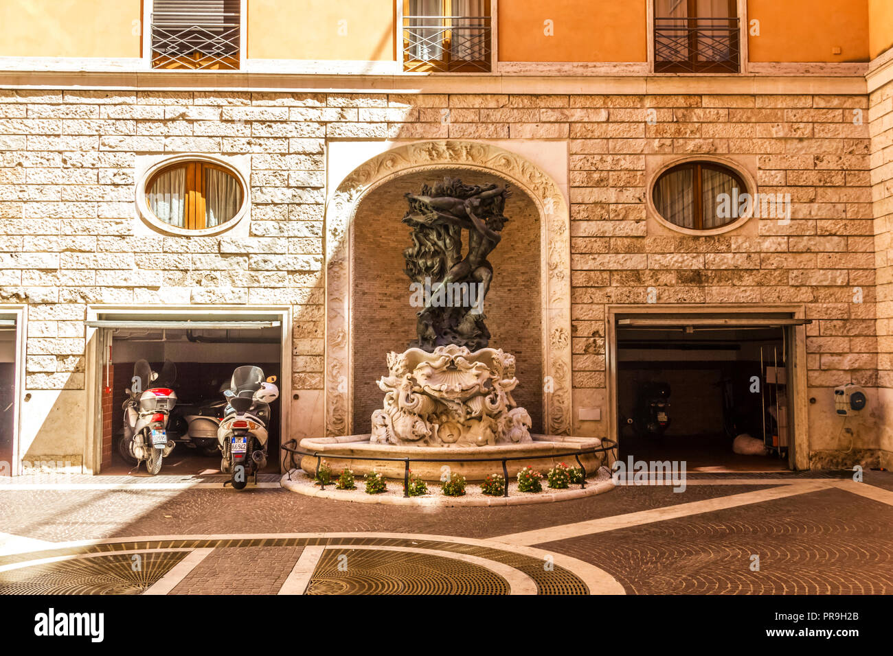 Rome/Italy - August 27, 2018: Scooter garage in the facade in front of a medieval fountain Stock Photo