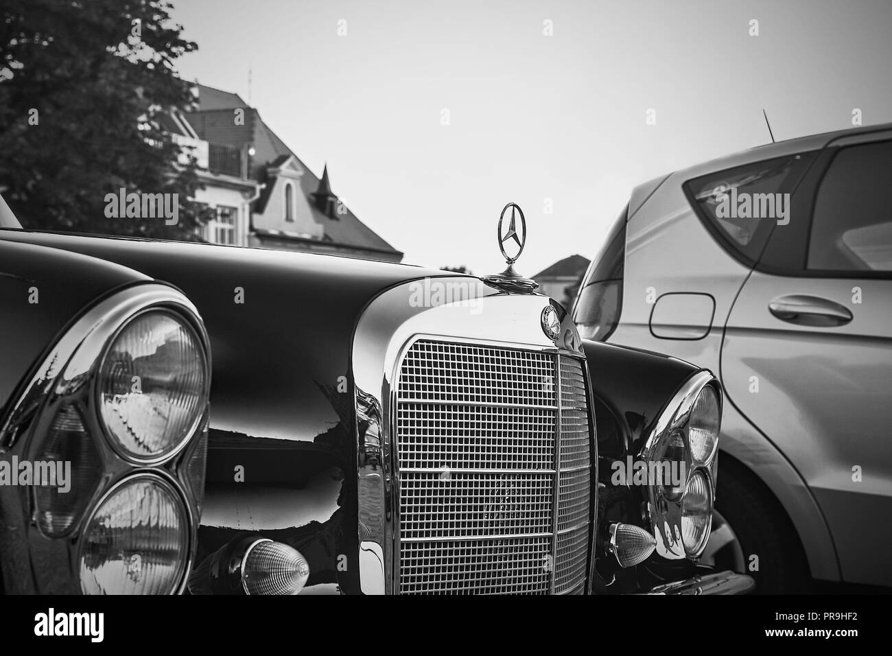Mercedes Benz logo on a black vintage car. Mercedes-Benz is a German automobile producer. The brand is used for luxury automobiles, buses, coaches and trucks. Black white filter. Stock Photo