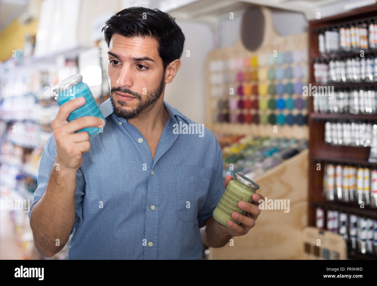Customer man looking instruction on paint near racks in paint shop
