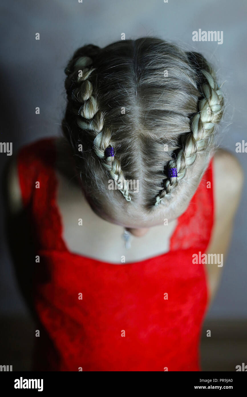 Two Braids On The Head Of A Girl In A Red Dress On A White