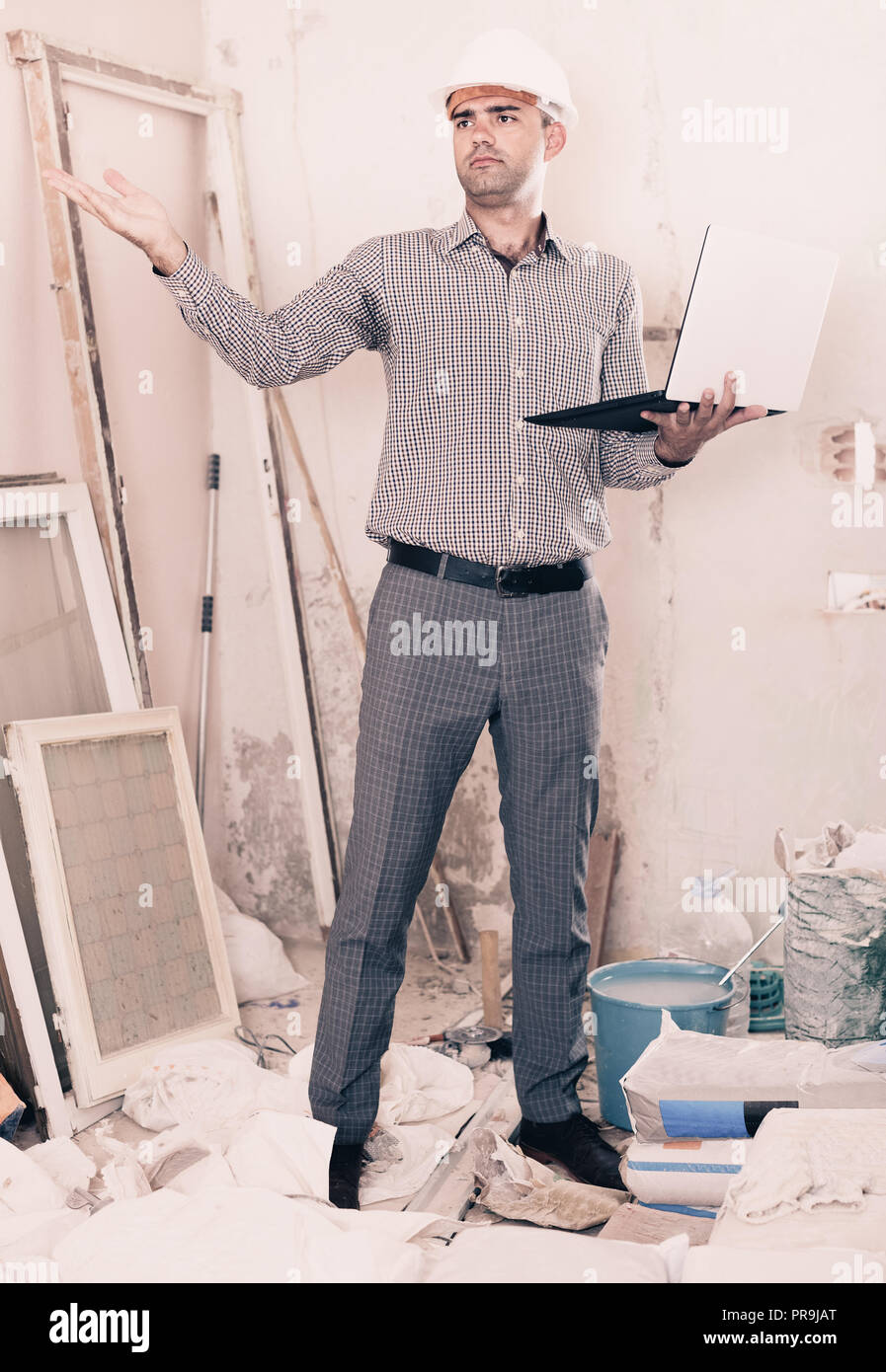 Engineer Adult Positive adult man engineer managing process with laptop in helmet ...