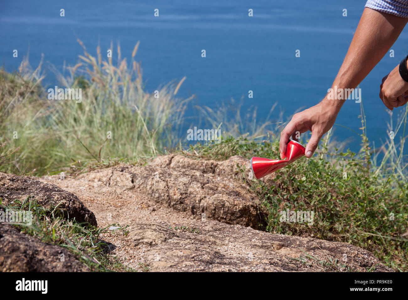 Man picking up litter can on rock at seaside Stock Photo - Alamy