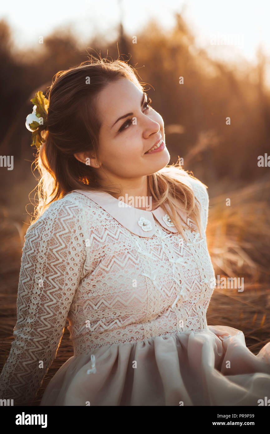 girl is sitting in the field on the sunset background Stock Photo - Alamy