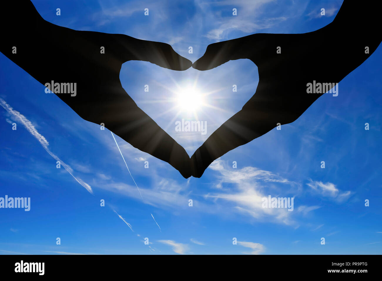 Hands of woman showing heart shape with a sunny blue sky in the ...