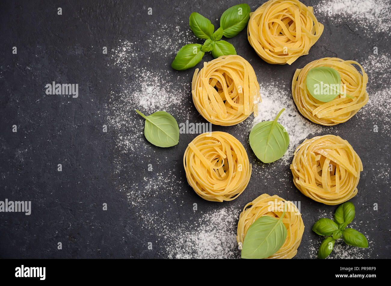 Raw tagliatelle pasta on the black concrete background Stock Photo